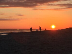 Ein Sonnenuntergang über einem Strand, Menschen spazieren.