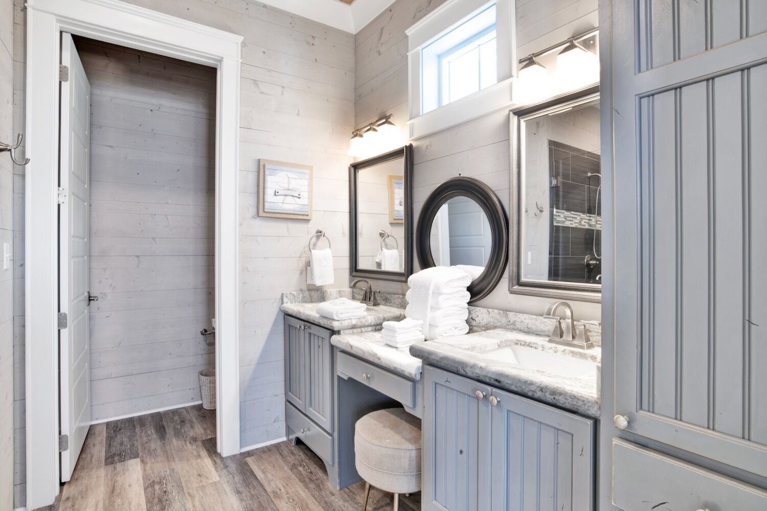 Une salle de bain avec un meuble-lavabo double, deux vasques, un grand miroir et un plancher en bois.