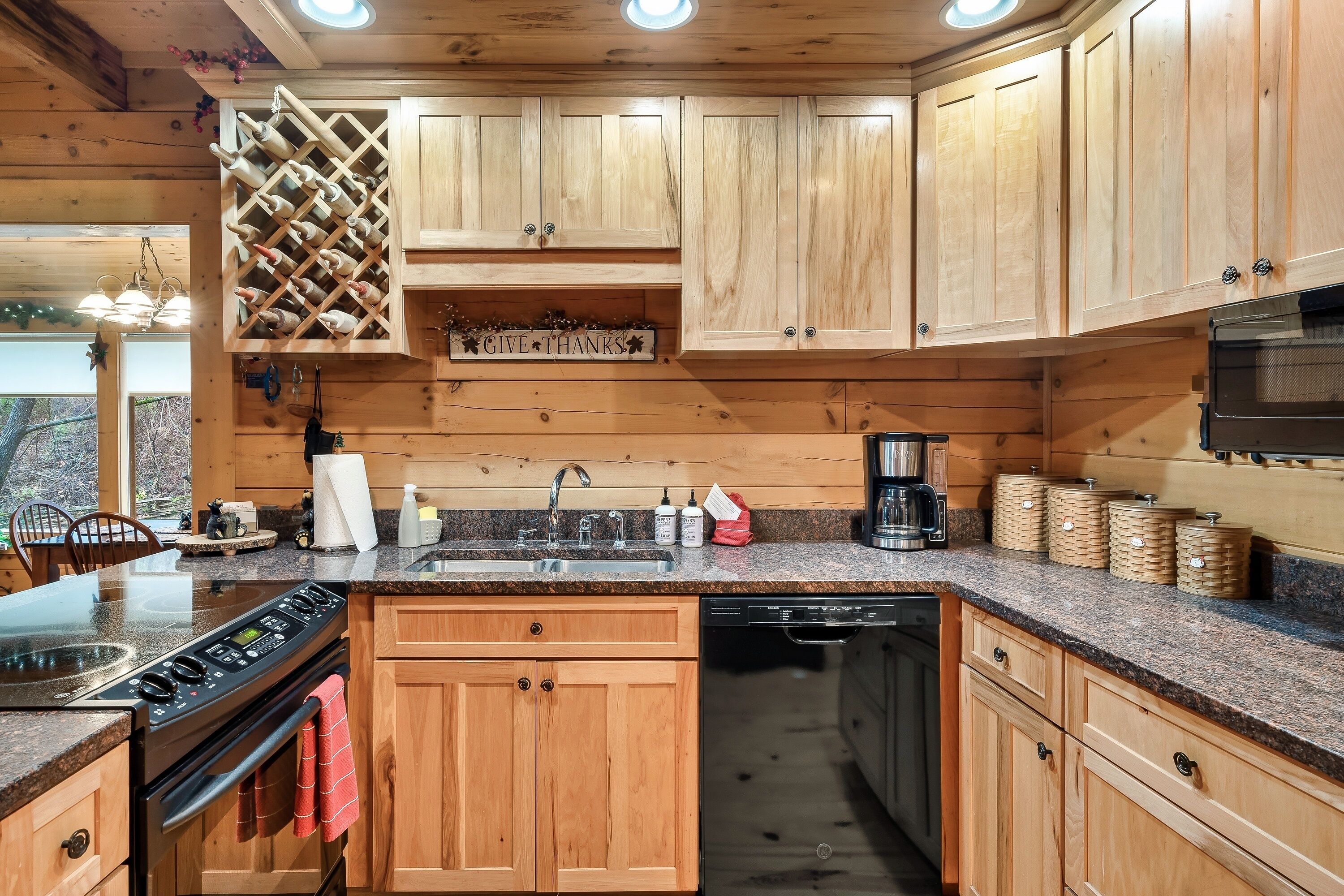 Une cuisine avec des meubles de rangement en bois, un meuble à vin intégré, un évier, une cuisinière et un lave-vaisselle.