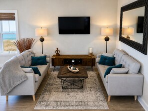 A living room with two sofas, a coffee table, a TV, and two lamps.