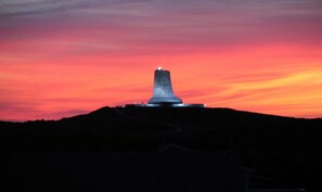 A monument on a hill with a sunset sky.