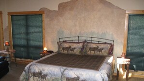 Una camera da letto con un letto grande, due comodini, una poltrona e una finestra con persiane.