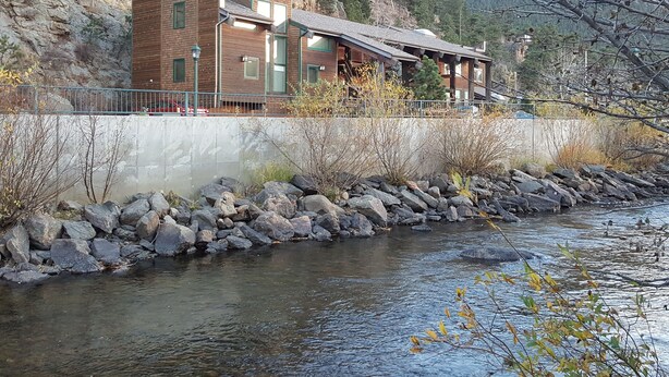 Un edificio moderno con facciata in pietra, tetto piatto e un fiume di fronte.