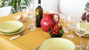 Ein Esstisch, gedeckt mit Tellern, Gläsern, einer roten Karaffe und einer Schüssel mit Tomaten.