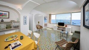 Ein Zimmer mit Esstisch, Stühlen, Fernseher und Meerblick.