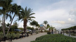 A coastal property with a gravel pathway, palm trees, and a water body. - Dbl Master |Oceanview |Jacuzzi |Beach |Marina |BBQ (Tavernier)
