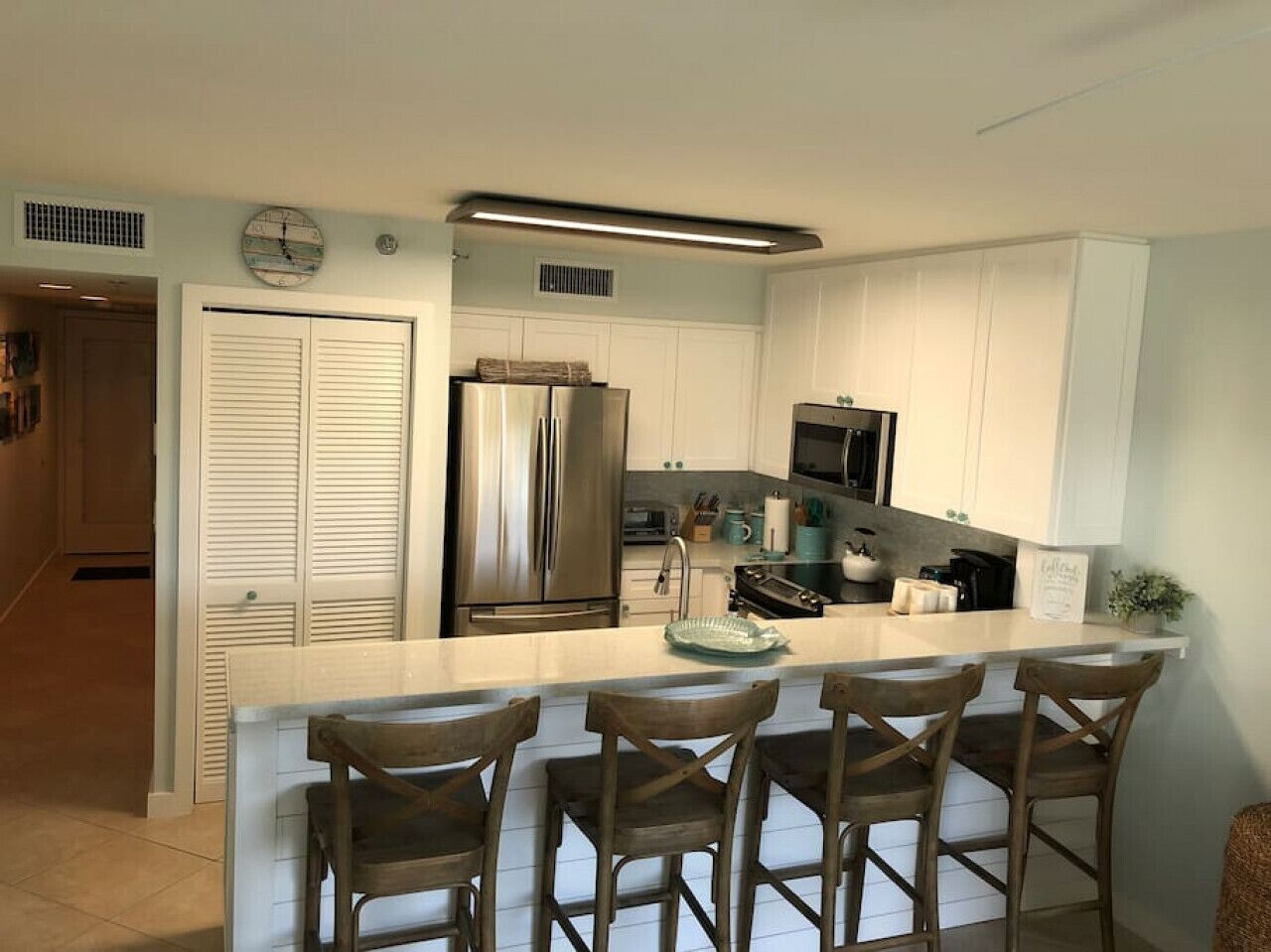 A modern kitchen with a central island, stainless steel appliances, and a bar seating area.