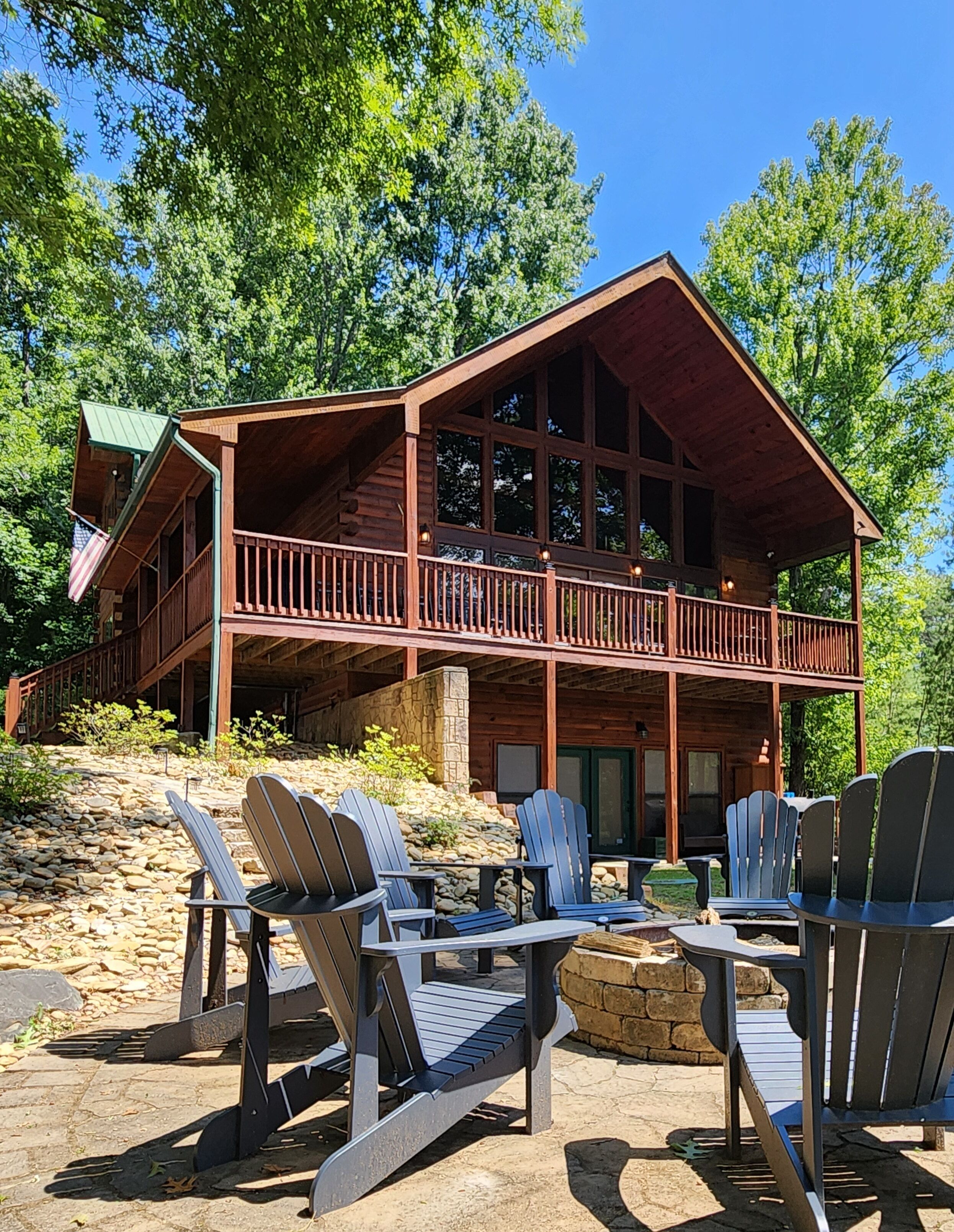 Een vakantiehuis van hout met een balkon, een terras met Adirondack stoelen en een stenen open haard.