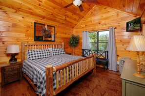 Ein Schlafzimmer einer Holzhütte mit einem Bett, einem Nachttisch, einer Lampe und einem Fernseher an der Wand.