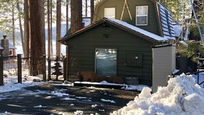 Une petite cabane avec un toit en pente, une cheminée et une paire de skis fixés à l’avant.