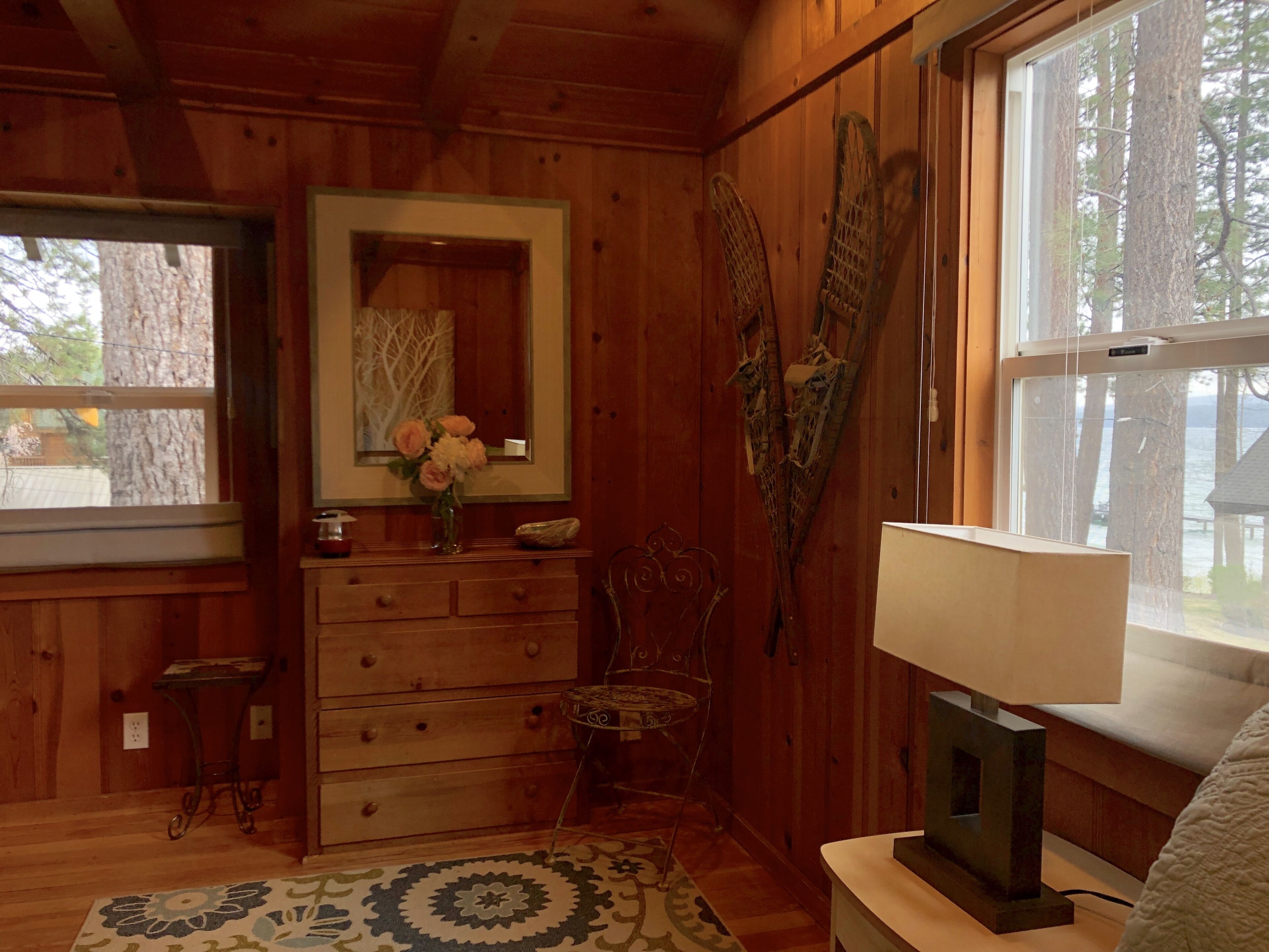 Een houten hut binnen met een dressoir, spiegel en een televisie op een standaard.