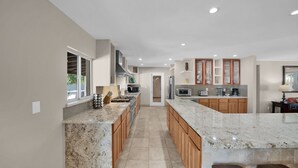 Una cocina moderna con encimeras de granito, armarios de madera y electrodomésticos de acero inoxidable.