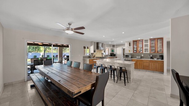 Una cocina amplia con una isla central, mesa de comedor de madera y taburetes de bar.