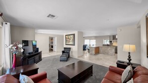 Amplia sala de estar con un conjunto de sofás, una mesa de centro, un televisor y un comedor con sillas.