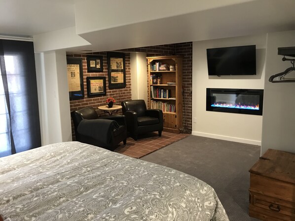 A bedroom with a large bed, a fireplace, a bookshelf, and framed pictures on the wall. - Aspen Ridge Mountain Getaway with Breathtaking Views, Wi-Fi (Divide)