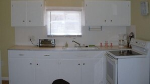 A compact kitchen with white cabinets, a built-in oven, and a toaster. - Sand Lake Cottage - near Tawas (National City)