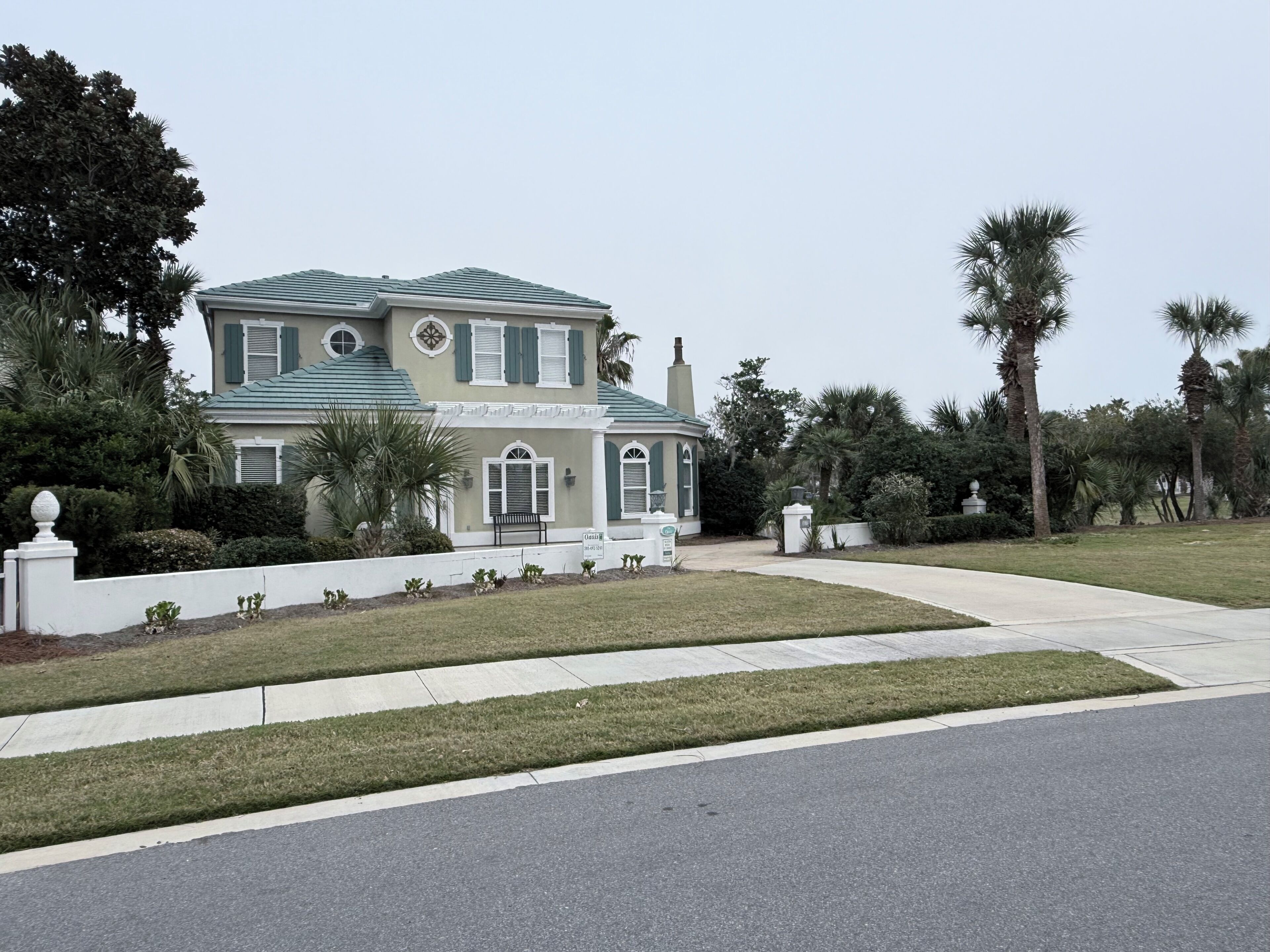 A two-story house with a green roof, a front porch, and a well-maintained lawn.