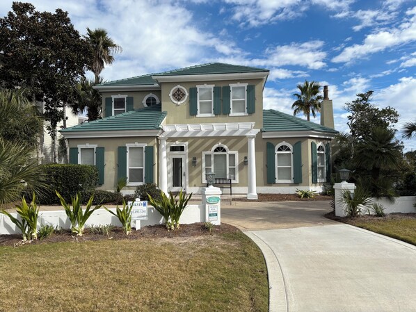 A two-story house with a green roof, white shutters, and a front porch.