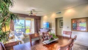 A dining area with a wooden table, chairs, a television, and a view of the outdoors.