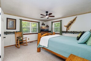 A bedroom with a bed, a rocking chair, a ceiling fan, and a wall-mounted TV. - Premier Riverfront Location ~ NEW BOATDOCK~ biking trails ~Bull Shoals Lake Fun (Lakeview)