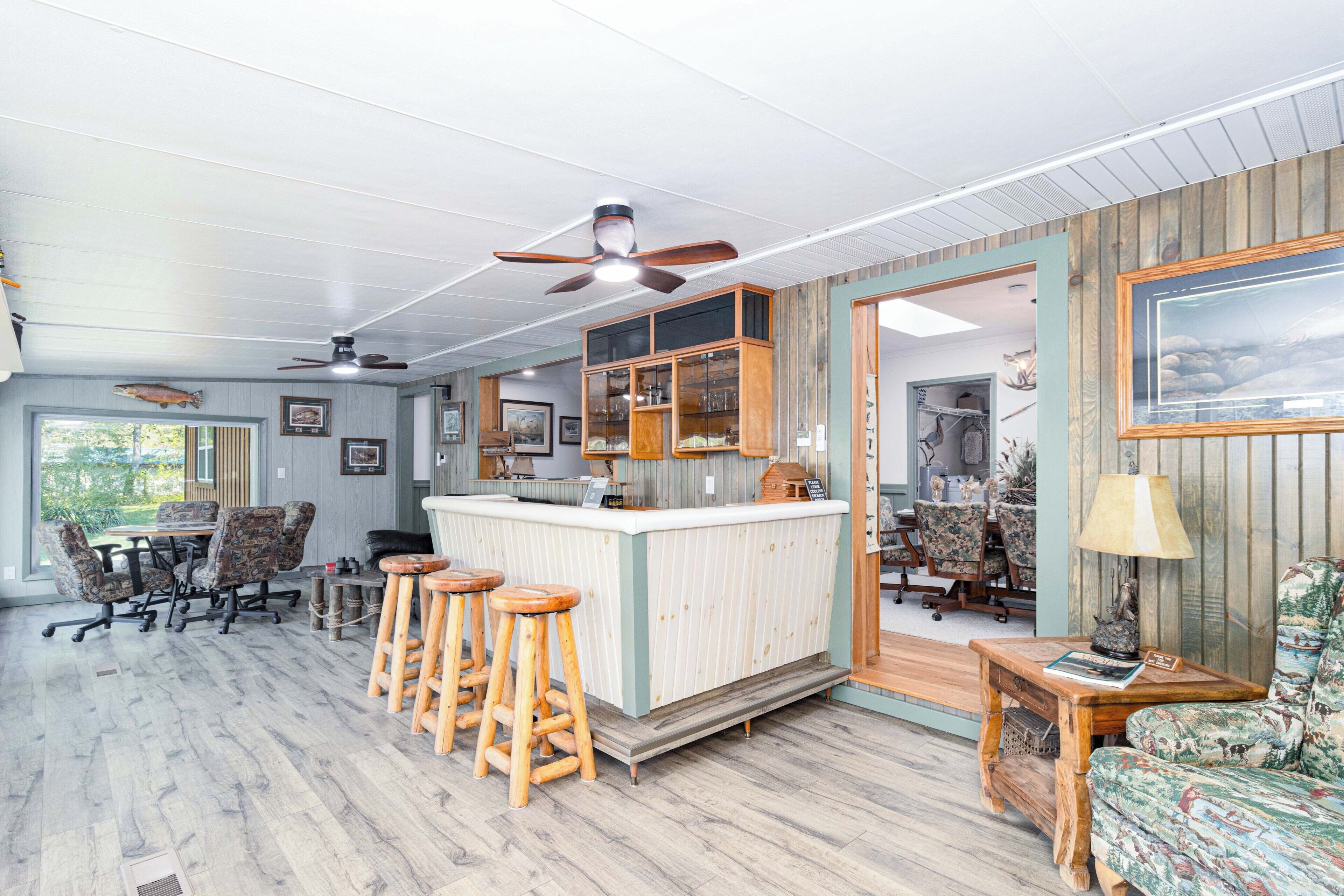 Un espace bar avec des tabourets, un comptoir et un ventilateur de plafond.