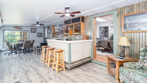 Uma área de bar com banquetas, balcão e ventilador de teto.