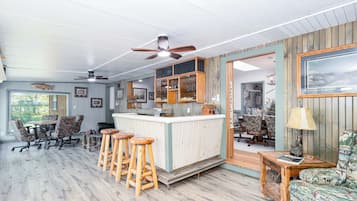 Un espace bar avec des tabourets, un comptoir et un ventilateur de plafond.