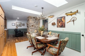 A dining area with a wooden table, chairs, a chandelier, and wall decorations including fish and a net.