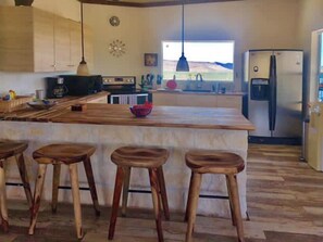 A kitchen with a large island, bar stools, a refrigerator, and a view of the outdoors. - Crystal Valley Cabin: Modern-Rustic Style&Comfort (Alpine)