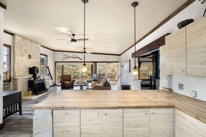 A spacious kitchen with a large island, stone accents, and a view of the outdoors. - Crystal Valley Cabin: Modern-Rustic Style&Comfort (Alpine)