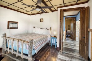 A bedroom with a wooden bed frame, a ceiling fan, a bedside table with a lamp, and a wooden door leading to another room. - Crystal Valley Cabin: Modern-Rustic Style&Comfort (Alpine)