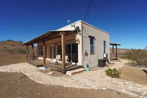 A single-story house with a covered porch, stone patio, and a clear blue sky. - Crystal Valley Cabin: Modern-Rustic Style&Comfort (Alpine)