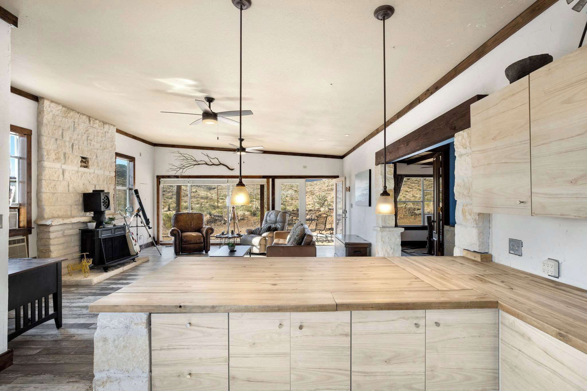 A spacious kitchen with a large island, stone accent wall, and modern pendant lighting.