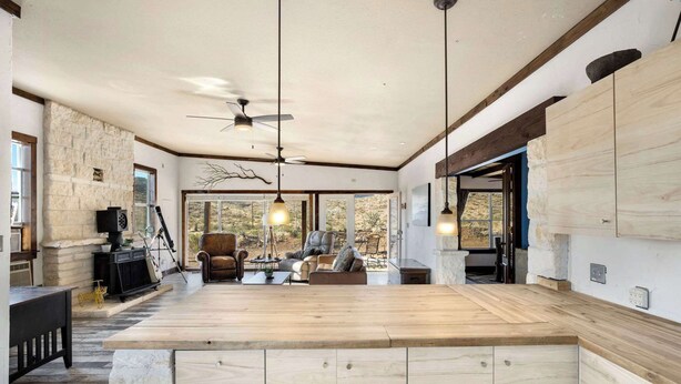 A spacious kitchen with a large island, stone accent wall, and modern pendant lighting.
