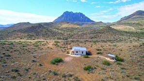 A remote, single-story building with a flat roof, surrounded by a dry, hilly landscape with sparse vegetation. - Crystal Valley Cabin: Modern-Rustic Style&Comfort (Alpine)