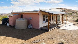 A small, single-story building with a covered patio and a water tank.