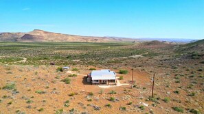 A single-story building with a flat roof, surrounded by a dry, hilly landscape. - Crystal Valley Cabin: Modern-Rustic Style&Comfort (Alpine)