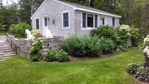 A small, single-story house with a stone wall and steps leading to the front door. - Come and enjoy our Boothbay Cottage (Boothbay Harbor)