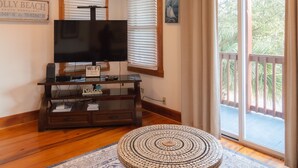 Ein Wohnzimmer mit Flachbildfernseher, einer Holz-Unterhaltungsecke und einem runden Couchtisch mit Mosaikplatte.