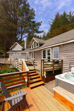 A wooden cabin with a hot tub, deck, and outdoor seating area. - Nautilus - Oceanfront Nantucket Style Home (Gold Beach)