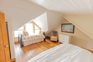 A bedroom with a bed, a chair, a dresser, and a painting on the wall. - Nautilus - Oceanfront Nantucket Style Home (Gold Beach)