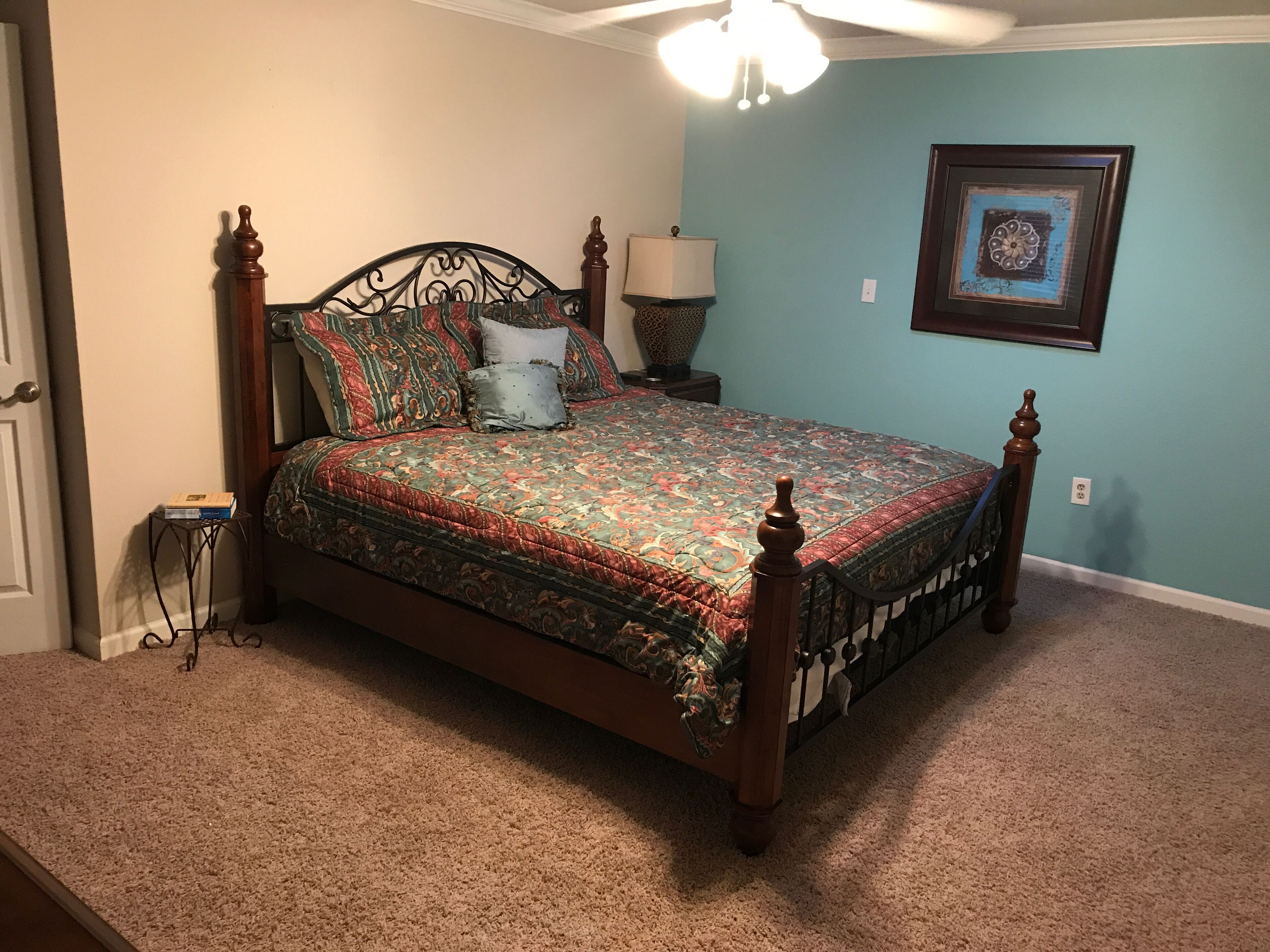 Un dormitorio con una cama con dosel, una mesita de noche, una lámpara y un cuadro en la pared.