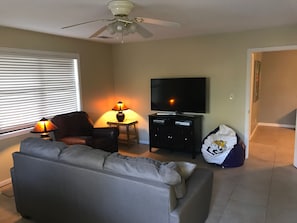 Relax in this stylish living room with a ceiling fan, flat-screen TV, and comfortable sofa.