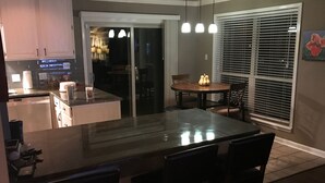 A kitchen with a central island, dining area with chairs, and a window with blinds. - House on Lake Hamilton Sleeps 17 in beds (Hot Springs)