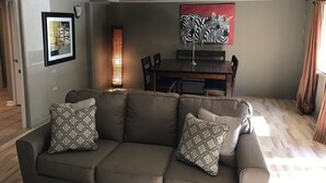 A living room with a sofa, patterned cushions, a dining table, chairs, a ceiling fan, and a painting on the wall. - House on Lake Hamilton Sleeps 17 in beds (Hot Springs)