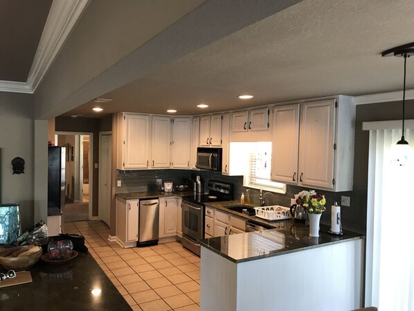 A spacious kitchen with white cabinets, a central island, stainless steel appliances, and a large window providing natural light. - House on Lake Hamilton Sleeps 17 in beds (Hot Springs)
