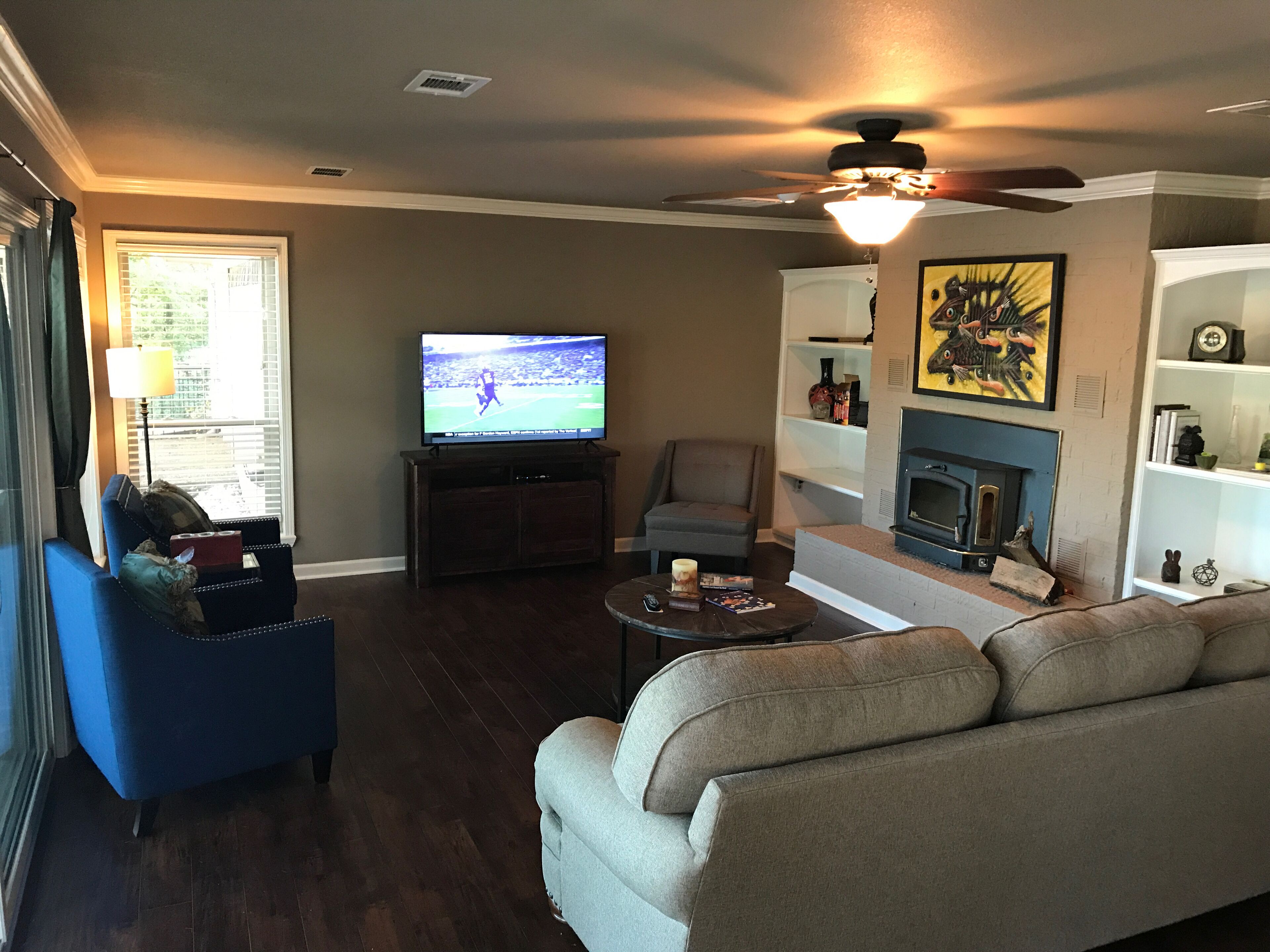 A living room with a television, a fireplace, a ceiling fan, and a sofa.