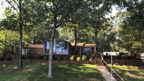 A two-story house with a large deck, surrounded by trees and a small pond. - House on Lake Hamilton Sleeps 17 in beds (Hot Springs)