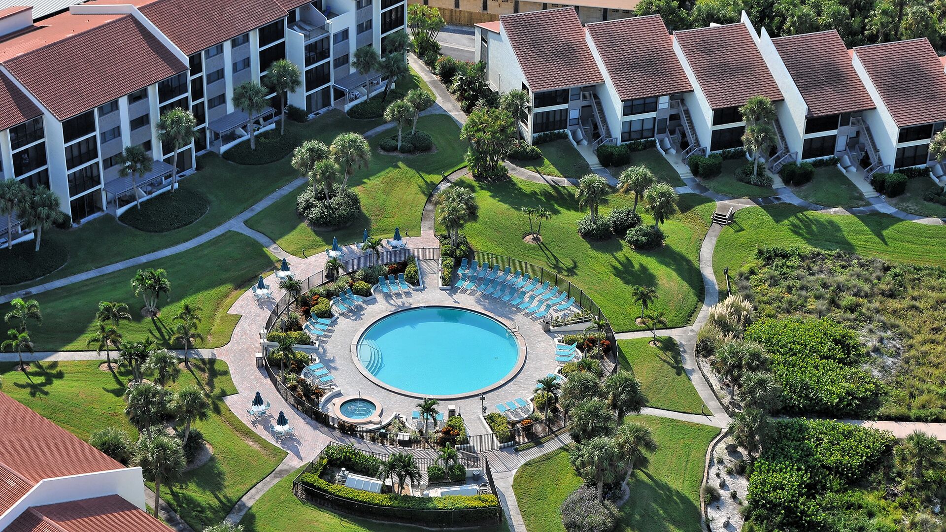 A resort with a central pool, multiple buildings, and well-maintained lawns.