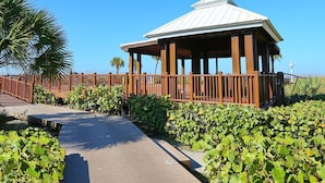 A gazebo with a metal roof and wooden pillars, surrounded by a wooden fence and lush greenery.